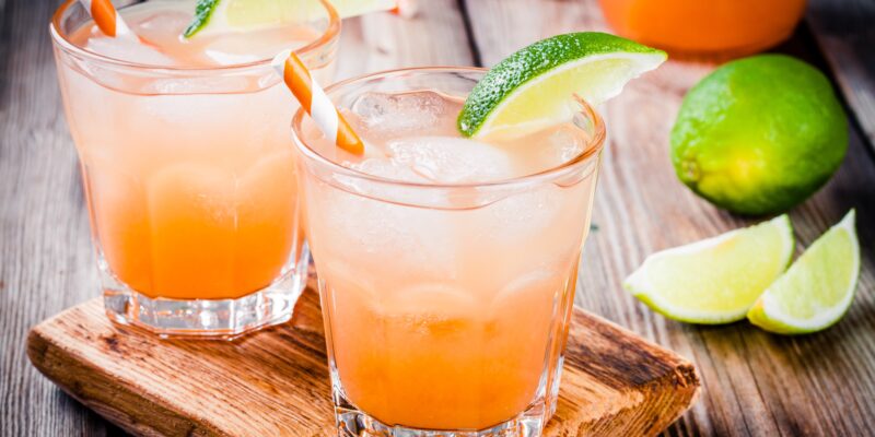 Tequila sunrise cocktail with ice and lime